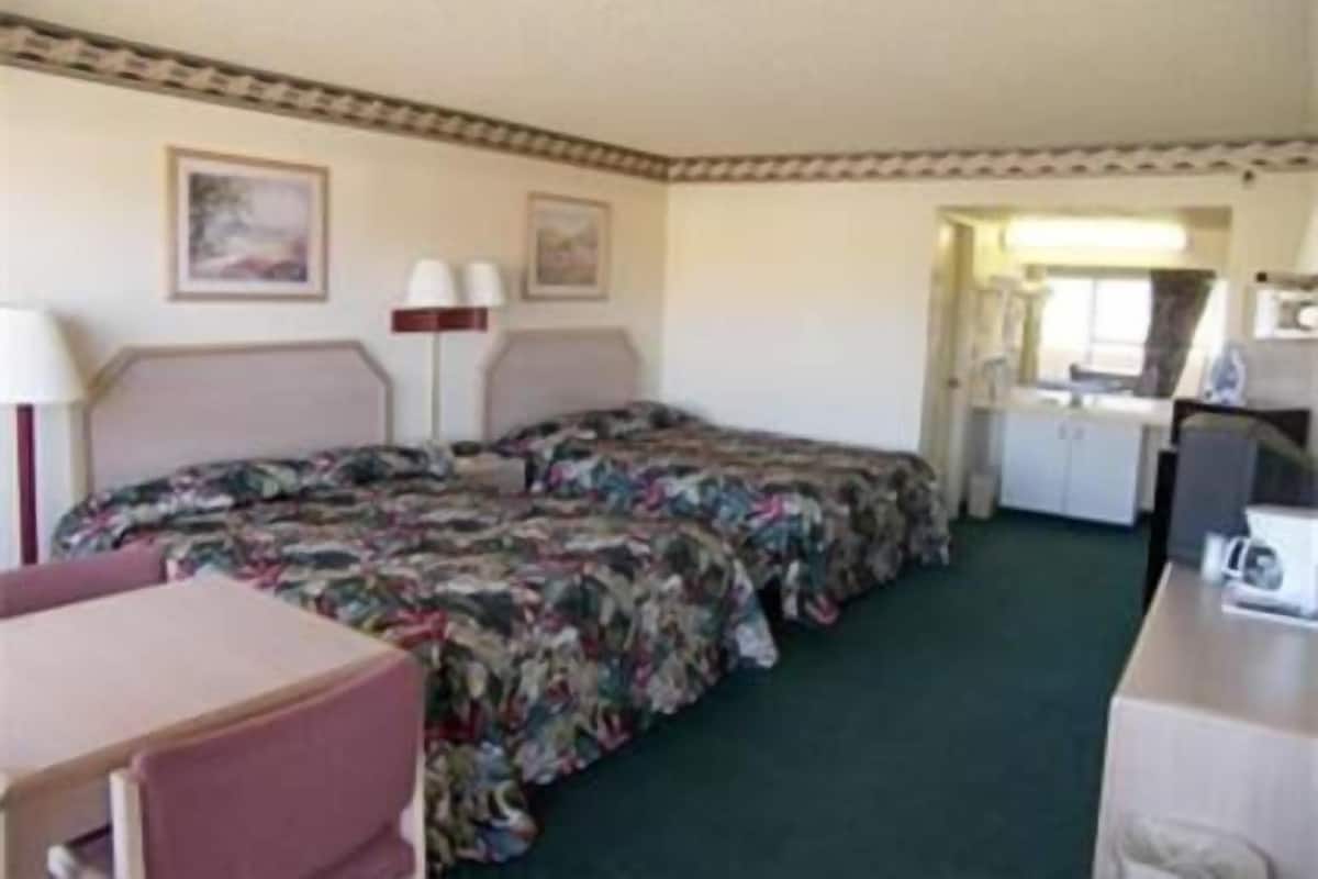 Une chambre comprenant un lit, un bureau, une chaise et un coin cuisine.