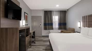 A hotel room with a bed, a desk, a television, and a door.