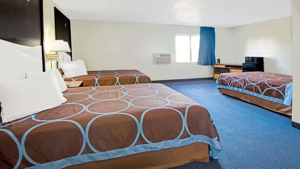 Een hotelkamer met twee bedden, een bureau, een televisie en een raam met gordijnen.