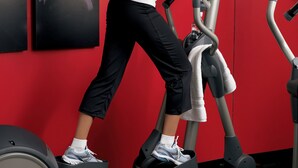 A woman using a stationary bike in a gym with red walls and multiple exercise machines. - Best Western Kennesaw (Kennesaw)