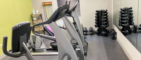 Een sportschool met trainingsapparatuur, waaronder loopbanden en gewichten.
