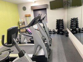 A gym with exercise equipment including treadmills and dumbbells.