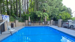 A clear blue pool surrounded by a fence, with chairs and umbrellas nearby. - Best Western Kennesaw (Kennesaw)