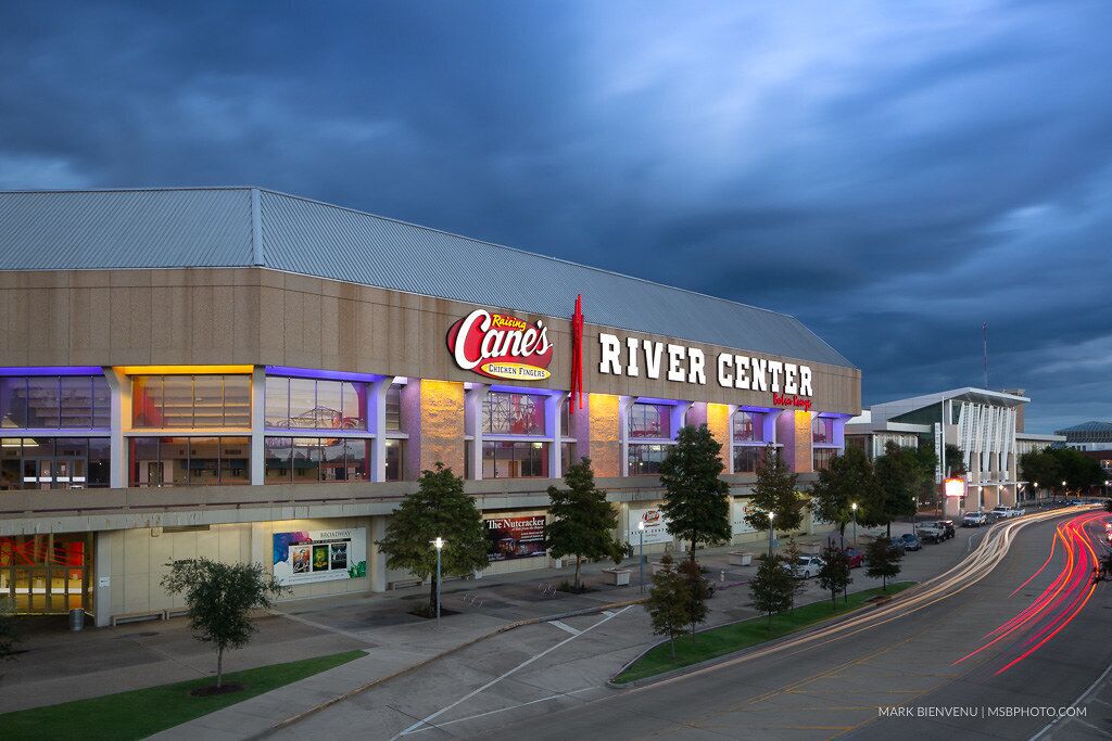 A large building with a sign reading "River Center" and "Rising Cane's."