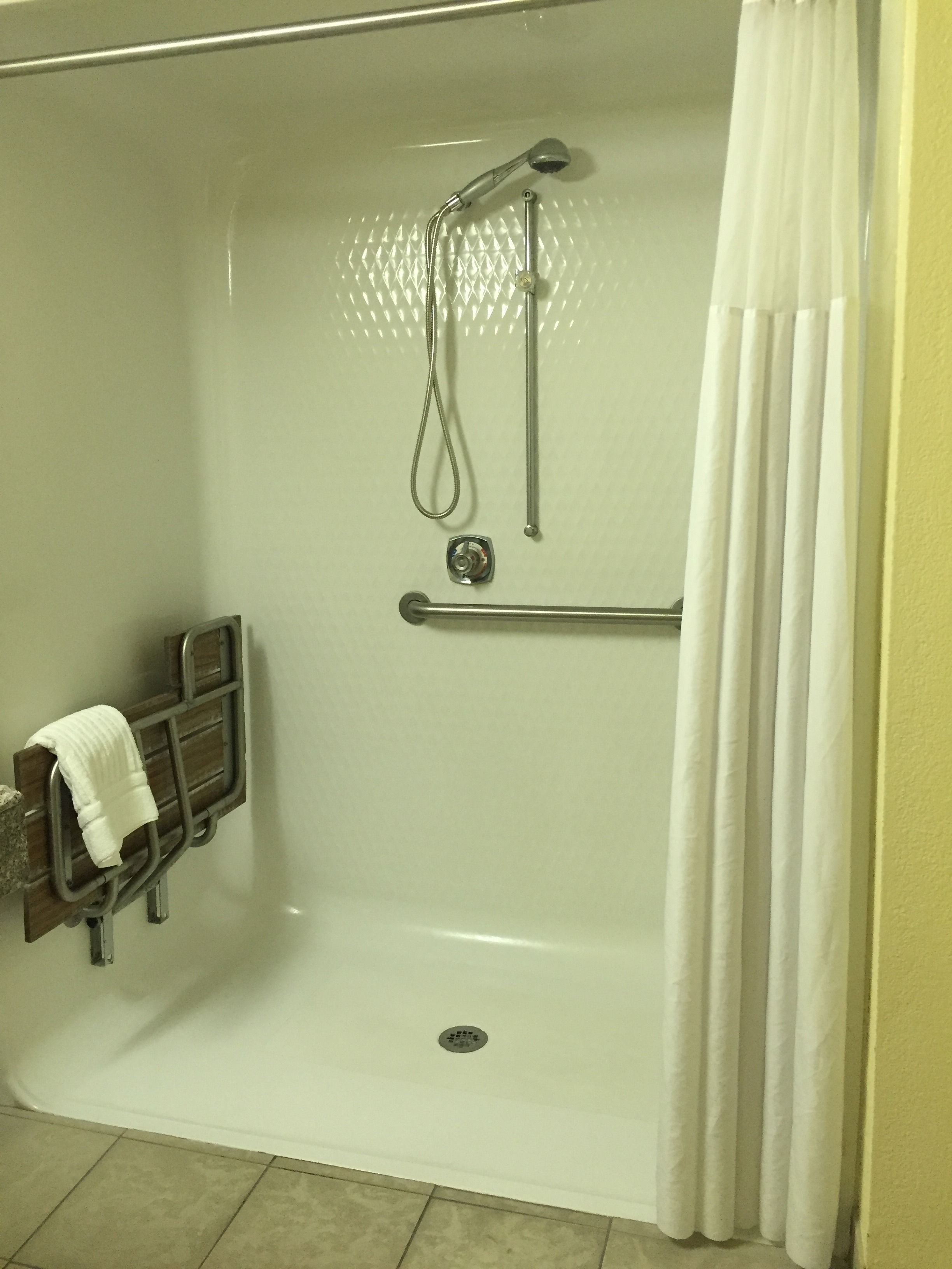 Une douche à l’italienne équipée d’une barre d’appui, d’un porte-serviettes et d’un pommeau de douche.