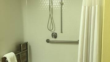 Une douche à l’italienne équipée d’une barre d’appui, d’un porte-serviettes et d’un pommeau de douche.