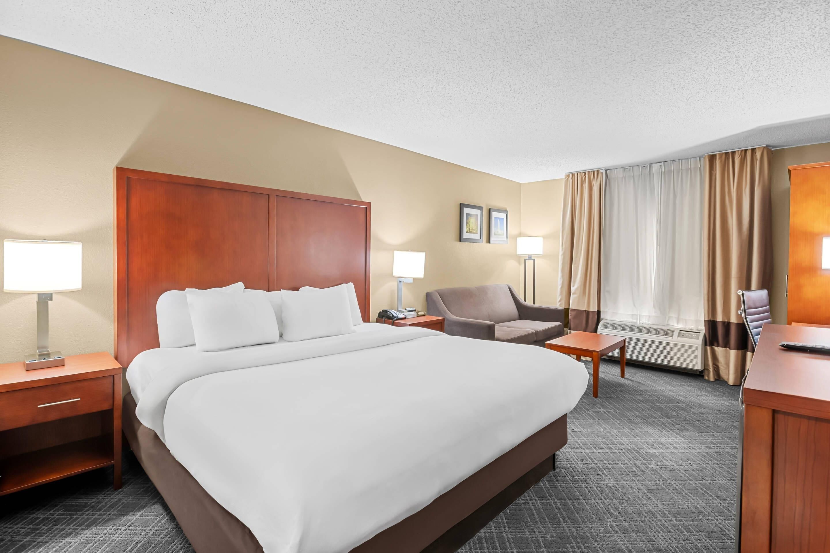 Ein Hotelzimmer mit einem großen Bett, einem Schreibtisch, einem Stuhl und einer Schreibtischlampe.