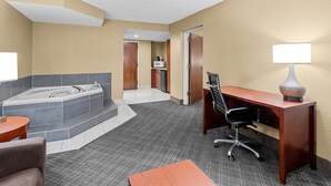 A hotel room with a large bathtub, a desk with a chair, a lamp, and a small table. - Comfort Inn University Area (Baton Rouge)