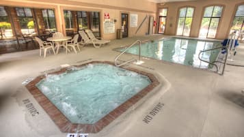 An indoor swimming pool with a hot tub, lounge chairs, and clear signage indicating no diving zones.