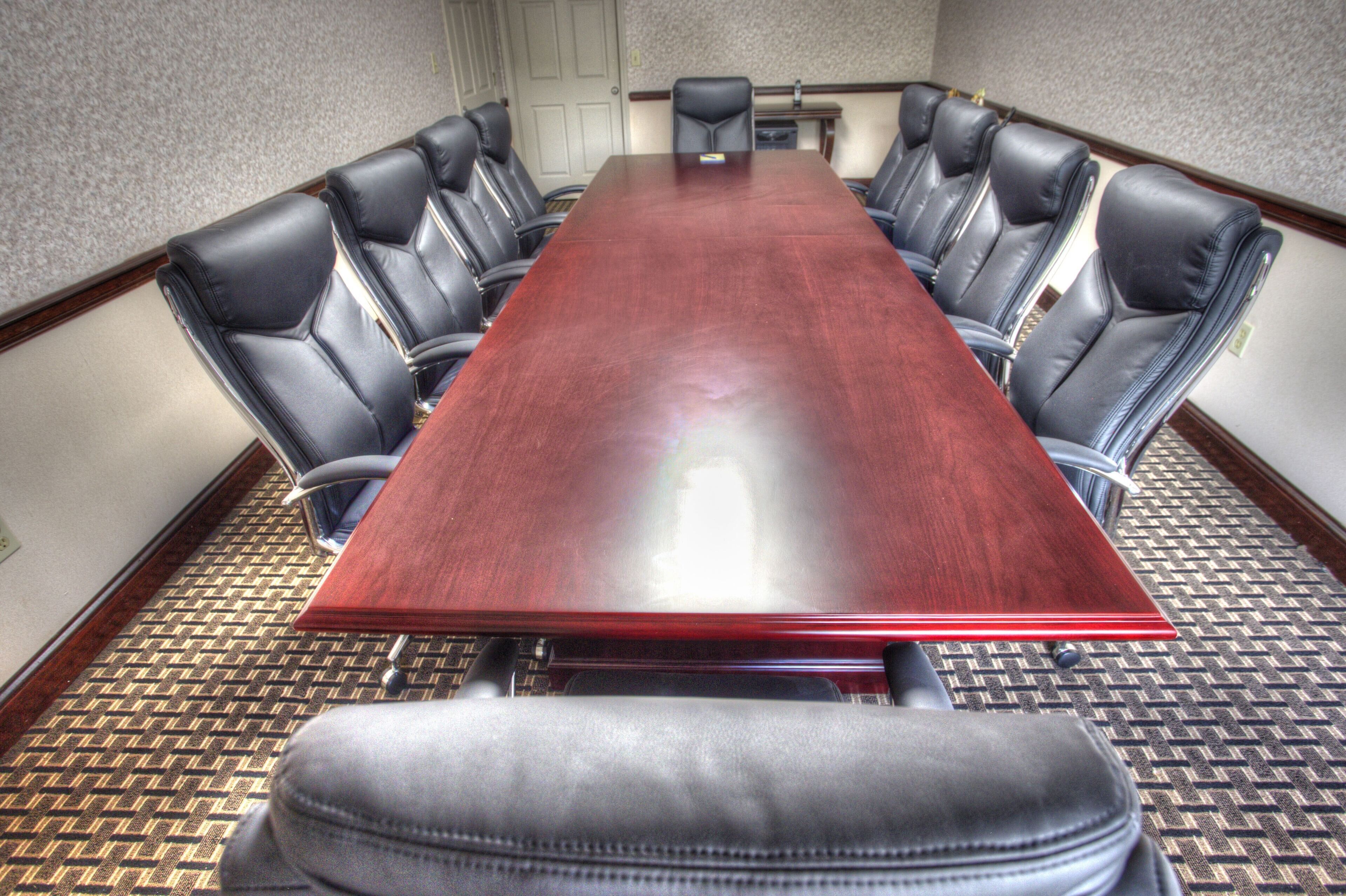 A conference room with a long wooden table surrounded by leather chairs.