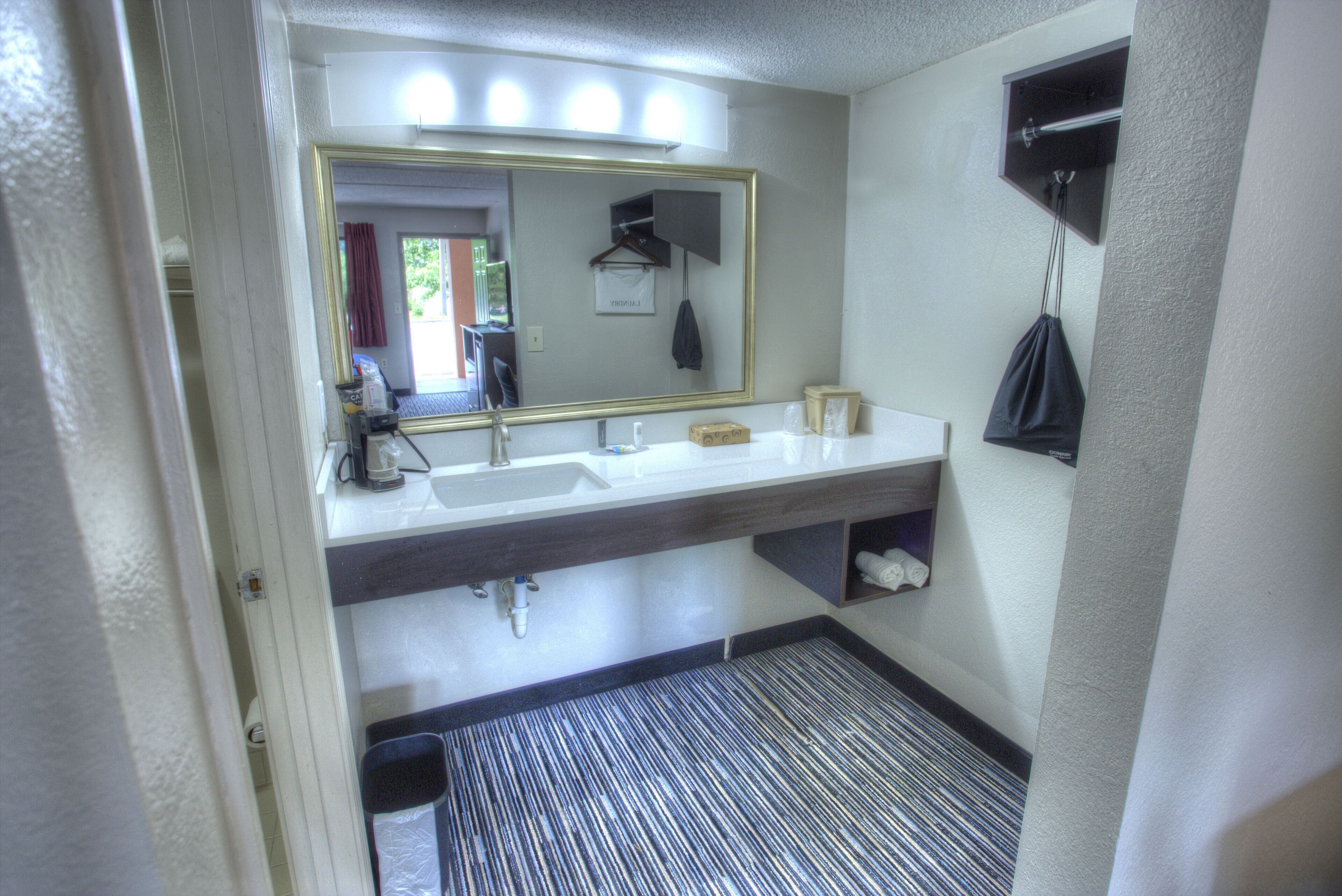 Une salle de bain dotée d’un grand miroir, de deux lavabos, d’un porte-serviettes et d’un espace douche.