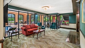 A spacious indoor area with a red sofa, green armchairs, and a pool view. - Econo Lodge Helen (Helen)