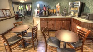 A restaurant with wooden tables and chairs, a coffee station, and a refrigerator with beverages. - Econo Lodge Helen (Helen)