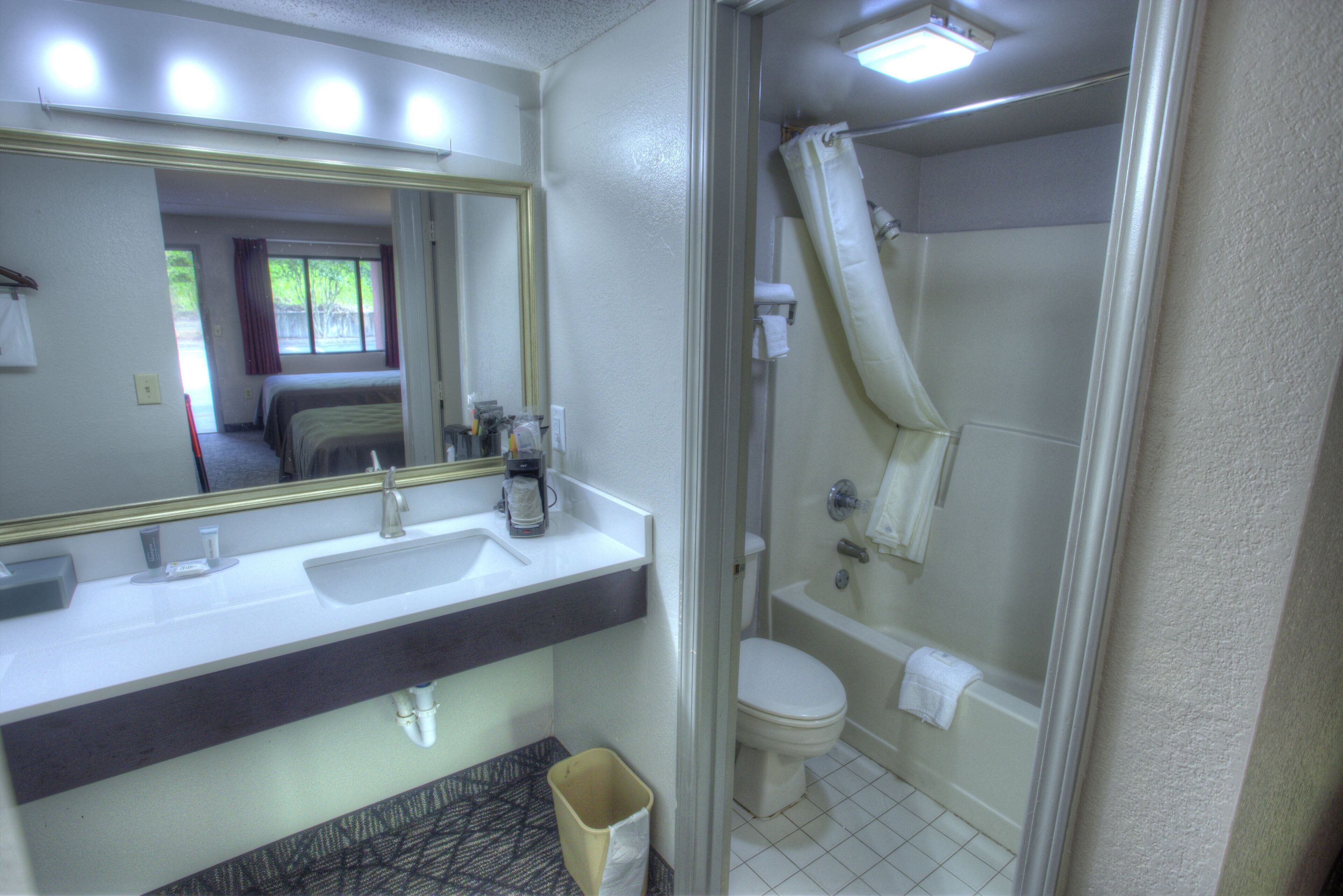 A bathroom with a sink, mirror, toilet, and shower.