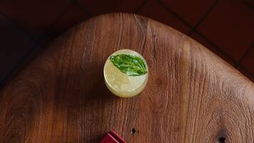 A glass of a light-colored beverage with a mint garnish on a wooden surface.