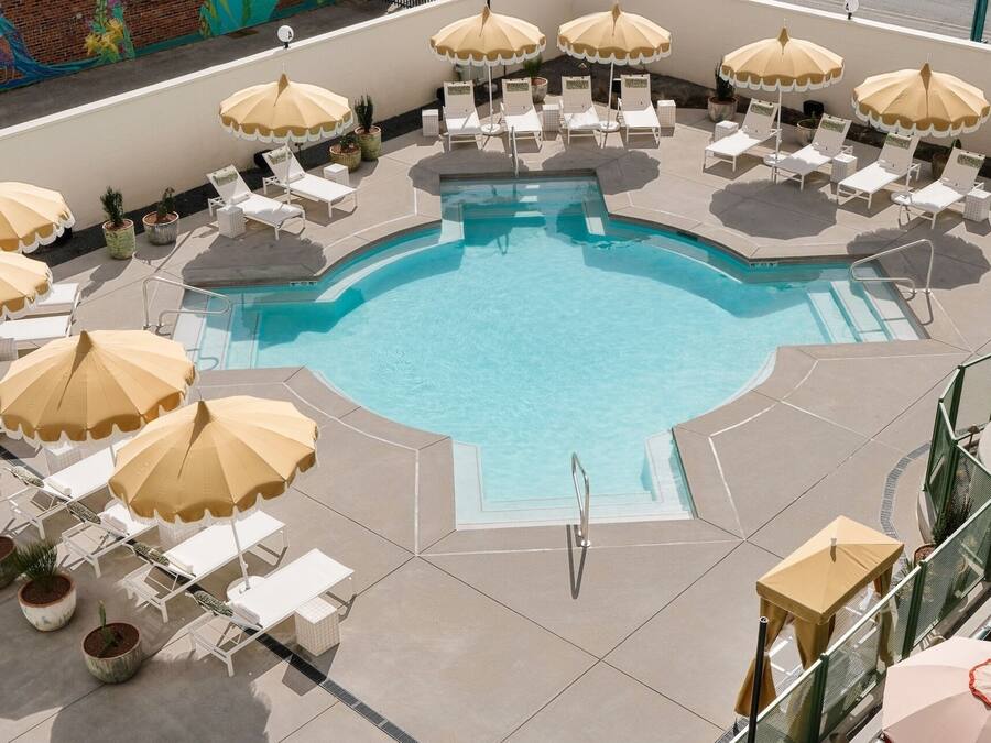 A pool area with multiple lounge chairs and umbrellas, surrounded by a tiled deck.