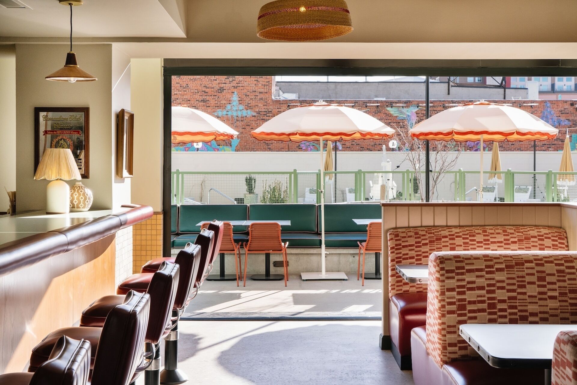 A restaurant with outdoor seating, green chairs, and orange umbrellas.