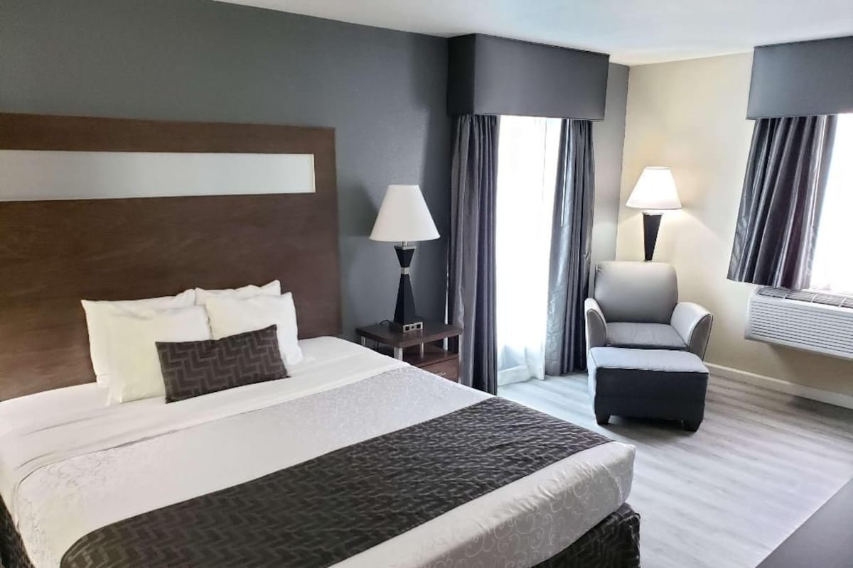 Habitación de hotel con una cama grande, una silla, un escritorio y una ventana con cortinas.