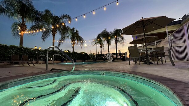 A pool area with a clear water surface, lounge chairs, and palm trees. - Best Western Americana (Dinuba)