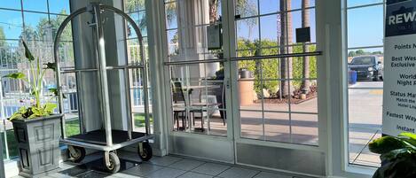 Um saguão de hotel com piso de azulejos, um carrinho e uma janela grande com vista para o exterior.