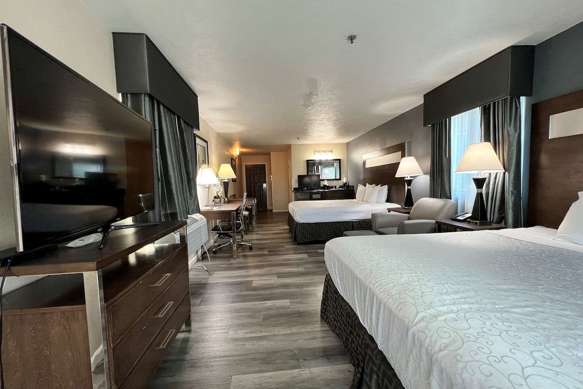 Una habitación de hotel con cama, escritorio, silla, televisor y armario.
