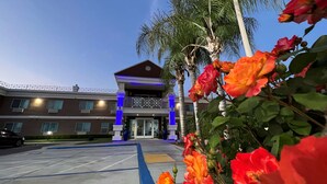 A hotel entrance with a modern design, featuring a prominent entrance with glass doors and a blue-lit structure. - Best Western Americana (Dinuba)
