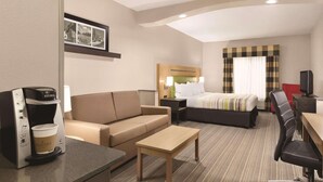 A hotel room with a bed, a sofa, a coffee maker, a TV, and a desk. - Country Inn & Suites by Radisson, Griffin, GA (Griffin)