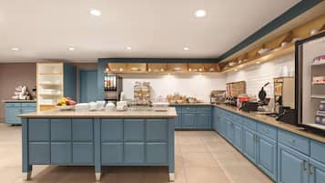A modern kitchen with a central island, blue cabinetry, and a white tiled backsplash.