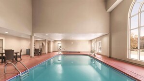 An indoor swimming pool with clear blue water, surrounded by a red deck and beige walls. - Country Inn & Suites by Radisson, Griffin, GA (Griffin)