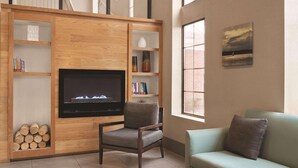 A living room with a fireplace, wooden shelving, a television, and a sofa. - Country Inn & Suites by Radisson, Griffin, GA (Griffin)
