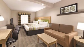 A hotel room with a bed, a sofa, a desk, a chair, and a television. - Country Inn & Suites by Radisson, Griffin, GA (Griffin)