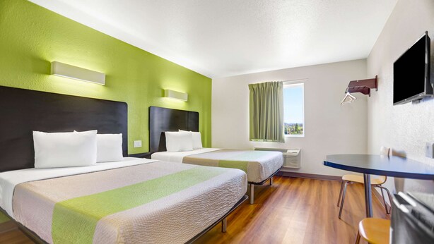A hotel room with two beds, a dining table, and a TV. - Motel 6 Silver City, NM (Silver City)