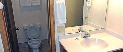 A bathroom with a toilet, a sink, and a mirror.