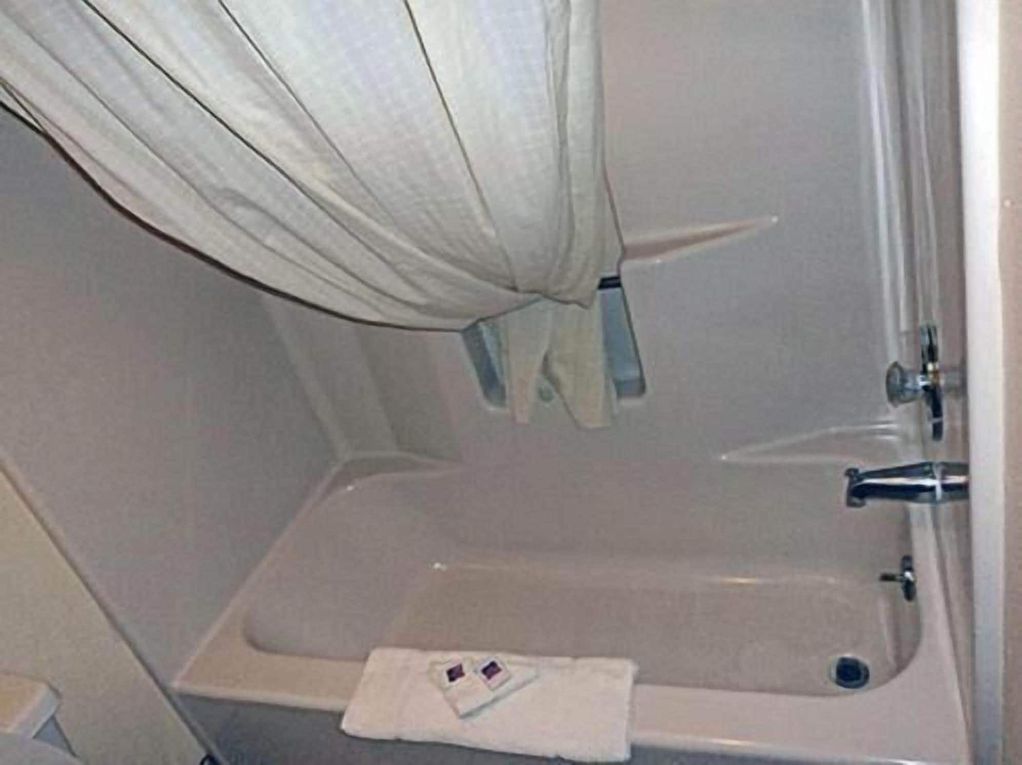 Un baño con bañera, una toalla y una cortina.