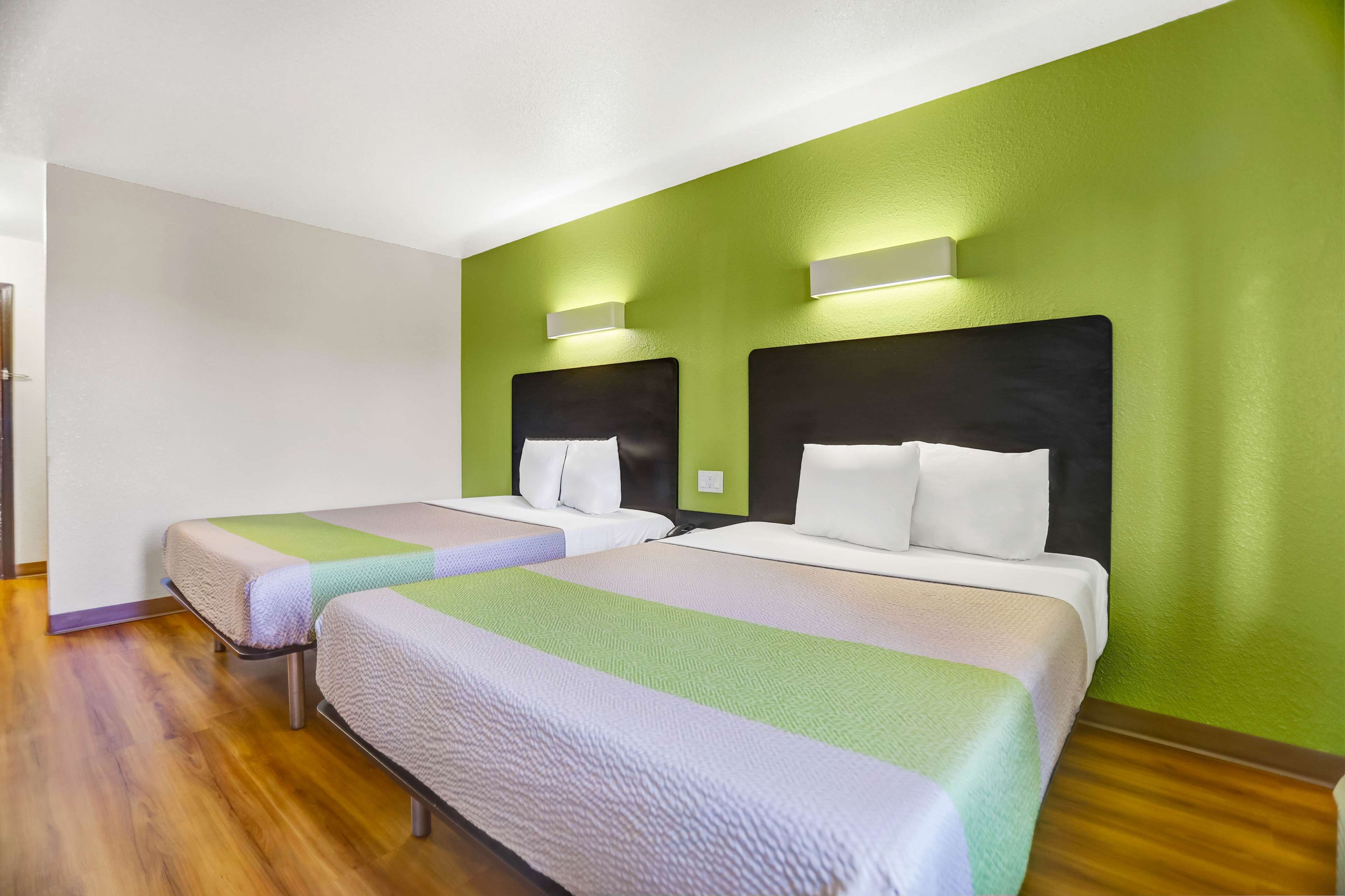 Une chambre d’hôtel avec deux lits, des murs verts et un plancher en bois.