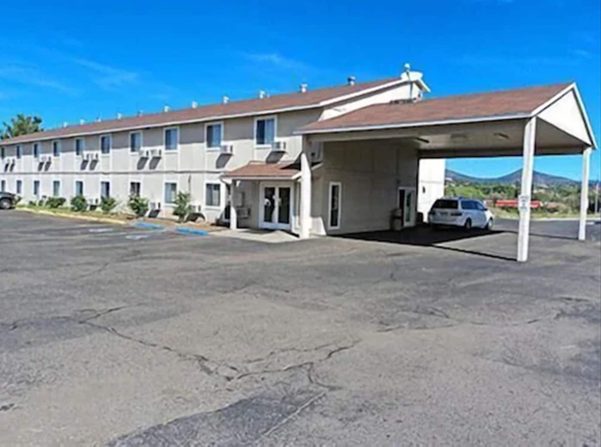 Un motel con zona de estacionamiento techada y una fila de habitaciones.