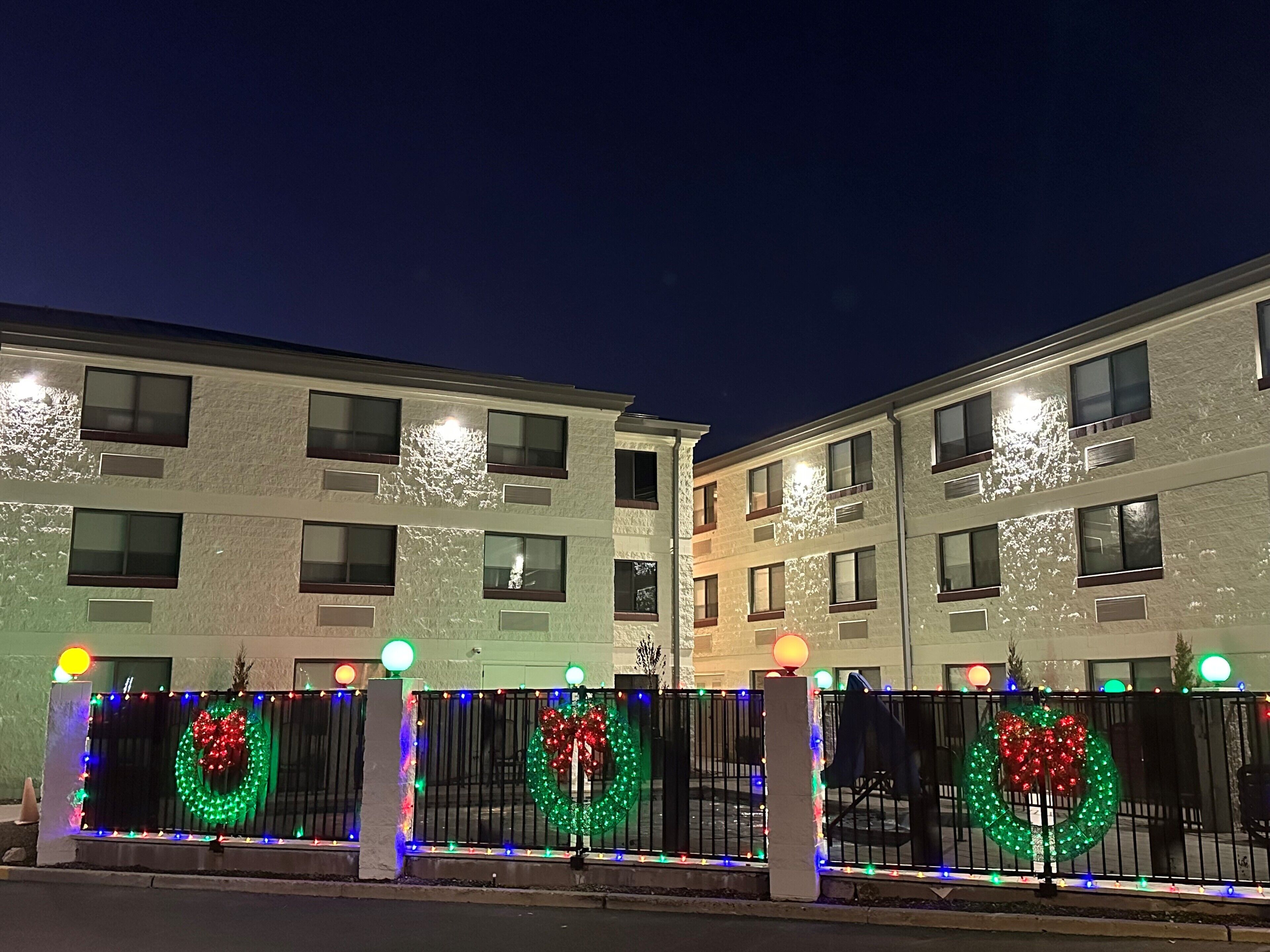 Een meerlaags gebouw met balkons en een hekpoort versierd met kerstkransen en lichtjes.