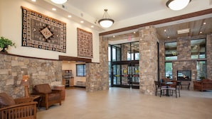 A spacious lobby with stone walls, wooden furniture, and large windows.