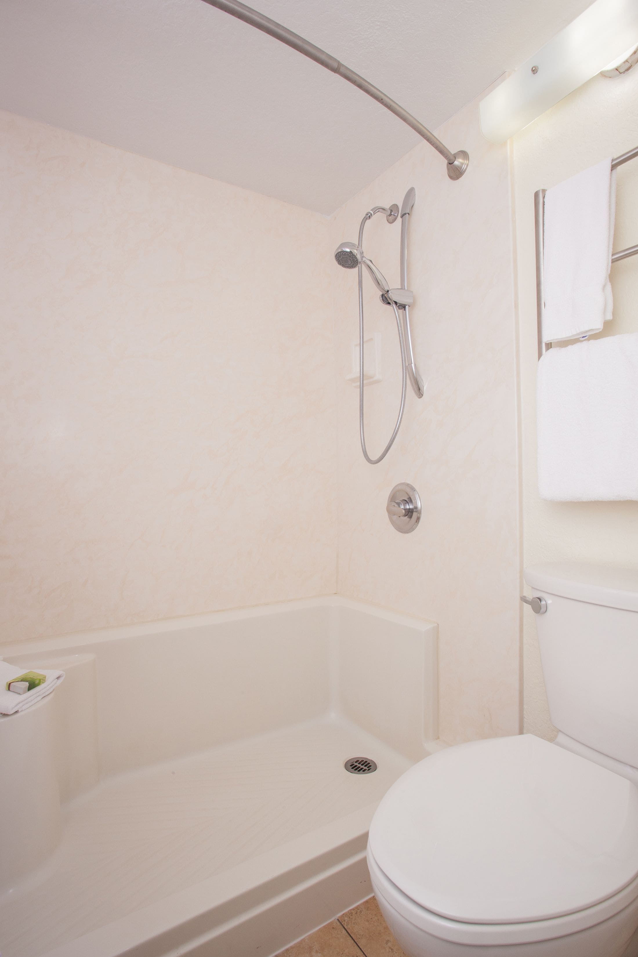 A bathroom with a shower, toilet, and a towel rack.