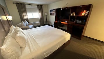 Ein Hotelzimmer mit einem großen Bett, einem Schreibtisch mit Computer, einem Fernseher und einer Minibar.