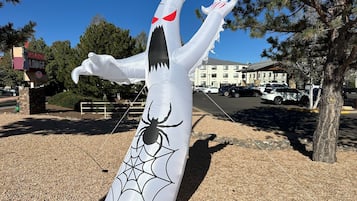 A large inflatable decoration resembling a spider with a web, located in an outdoor area with a building and parked cars in the background.