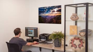 A workspace with a computer, printer, and a glass display case with pottery.