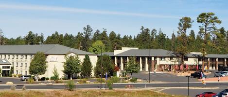 A hotel with multiple buildings, a parking lot, and a forested area in the background.