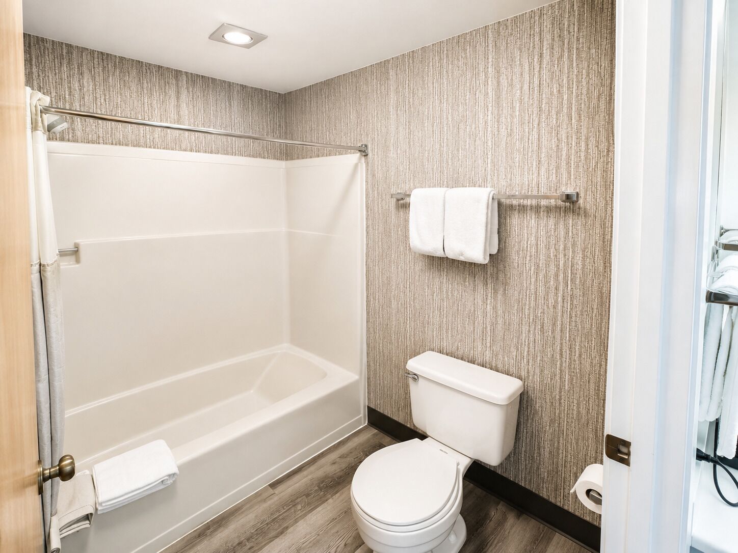 A bathroom with a bathtub, toilet, and a towel rack.
