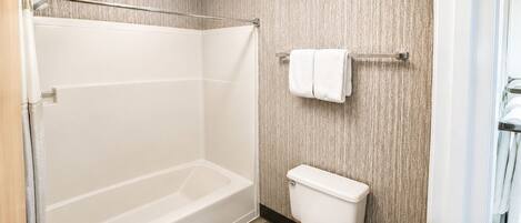 A bathroom with a bathtub, toilet, and a towel rack.