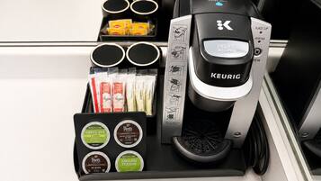 A Keurig coffee machine with a water reservoir, a coffee pod holder, and a tray with coffee pods.
