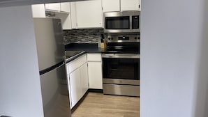 A kitchen with white cabinets, a stainless steel refrigerator, a microwave, and an oven. - Seabird Lodge (Fort Bragg)
