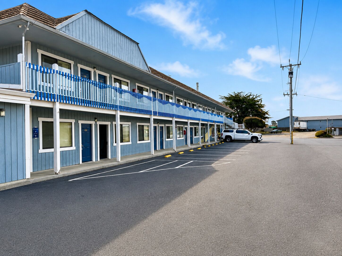Un motel con una fila di camere, un parcheggio e un cielo sereno.