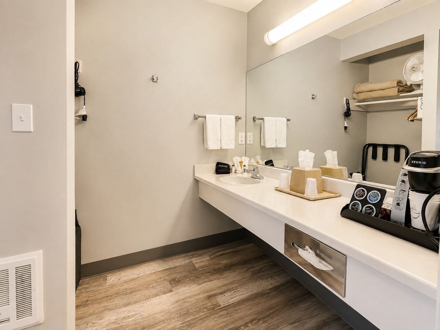 A modern bathroom with a white sink, mirror, and a coffee machine.