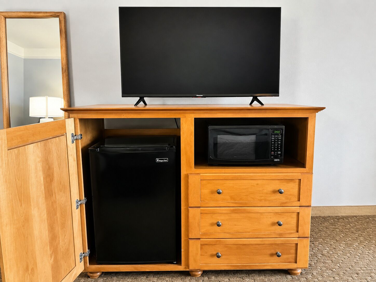 A wooden cabinet with a television, a microwave, and a refrigerator.